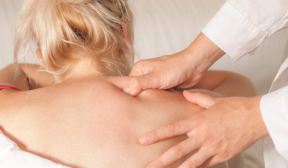 Chiropractor applying trigger point therapy to a patient’s upper back to release muscle tension and pain